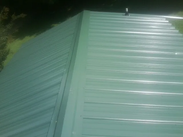 New green metal panels meeting at the ridge of a roof — Flat Roof Repair work by our crew in Spangle