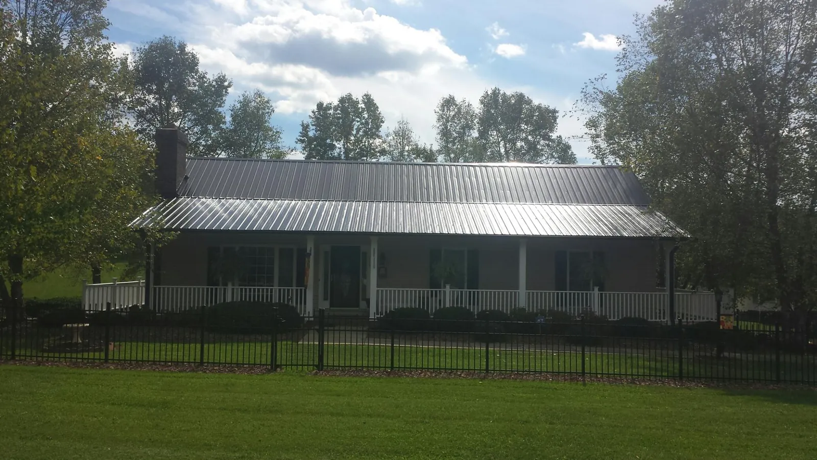 Gray metal roof on a brick ranch with a full width front porch — Gutter Guard Installation work by our crew in Spangle