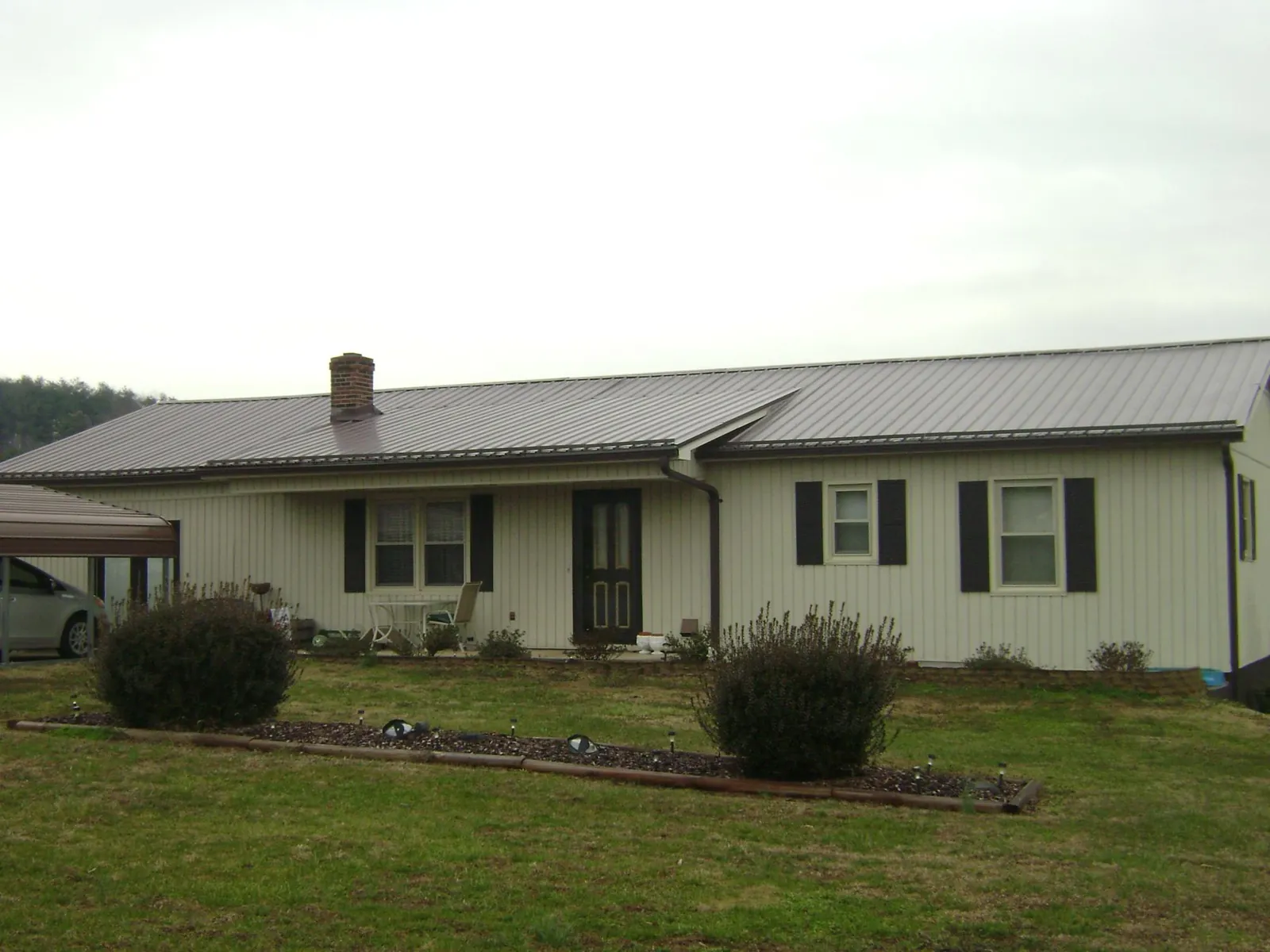 Brown metal roof on a cream sided ranch home with a brick chimney in Spangle